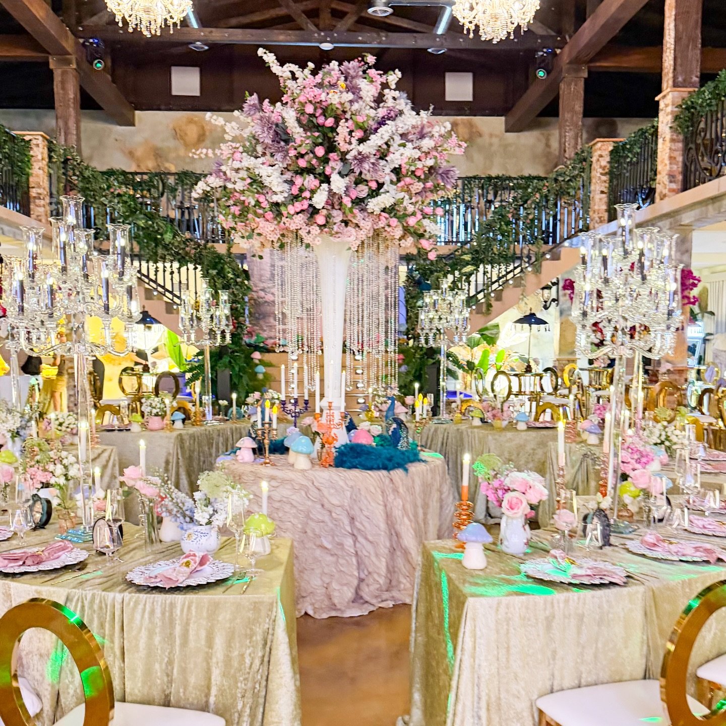 Mesa principal con mantelería dorada, centro floral de rosas pastel y cristalería de gala.