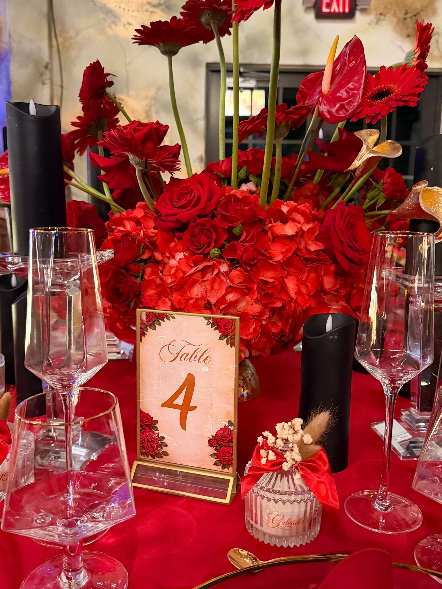 Detalle de mesa: arreglo de rosas rojas, gerberas e hortensias en mesa de gala.